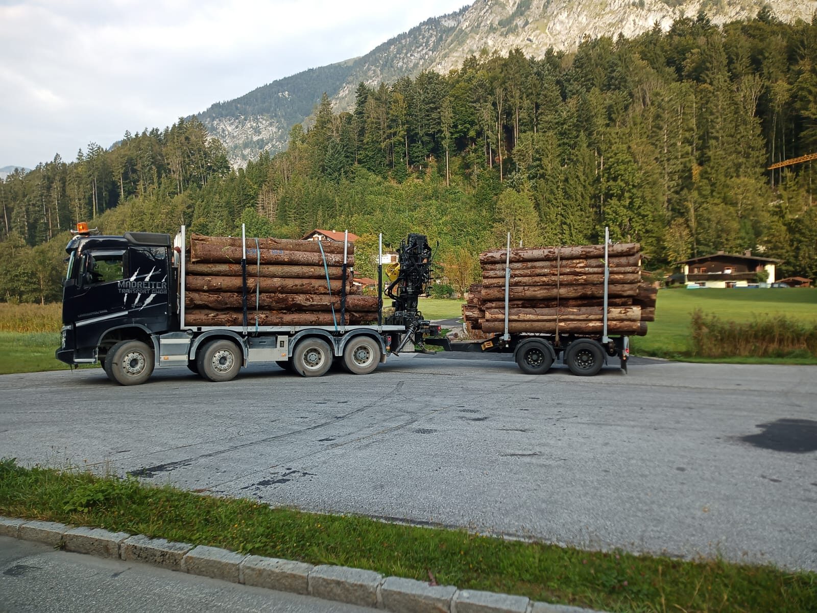 Schwarzer Holztransporter von Madreiter vor Tiroler Bergkulisse